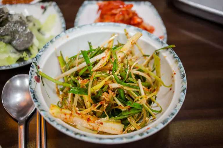 Close-up shot of scallion kimchi served in a ceramic bowl, showcasing Asian cuisine.