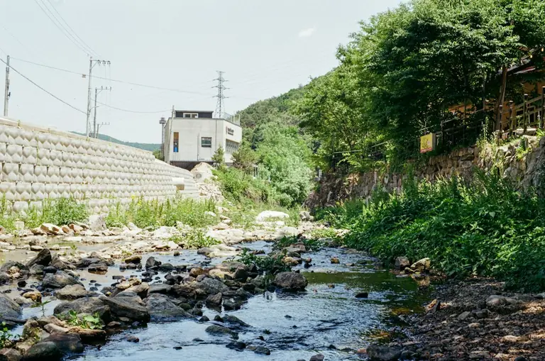A rocky stream flows past a building.